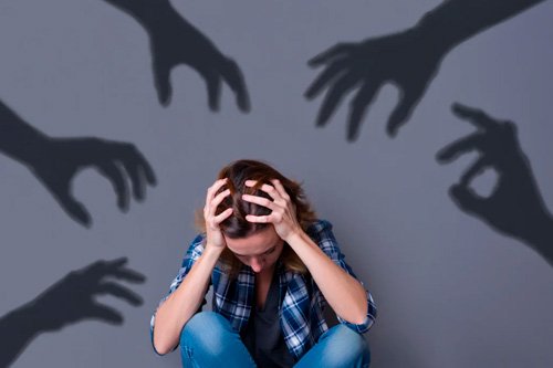 Девушка сидит на полу К девушке тянутся тени рук